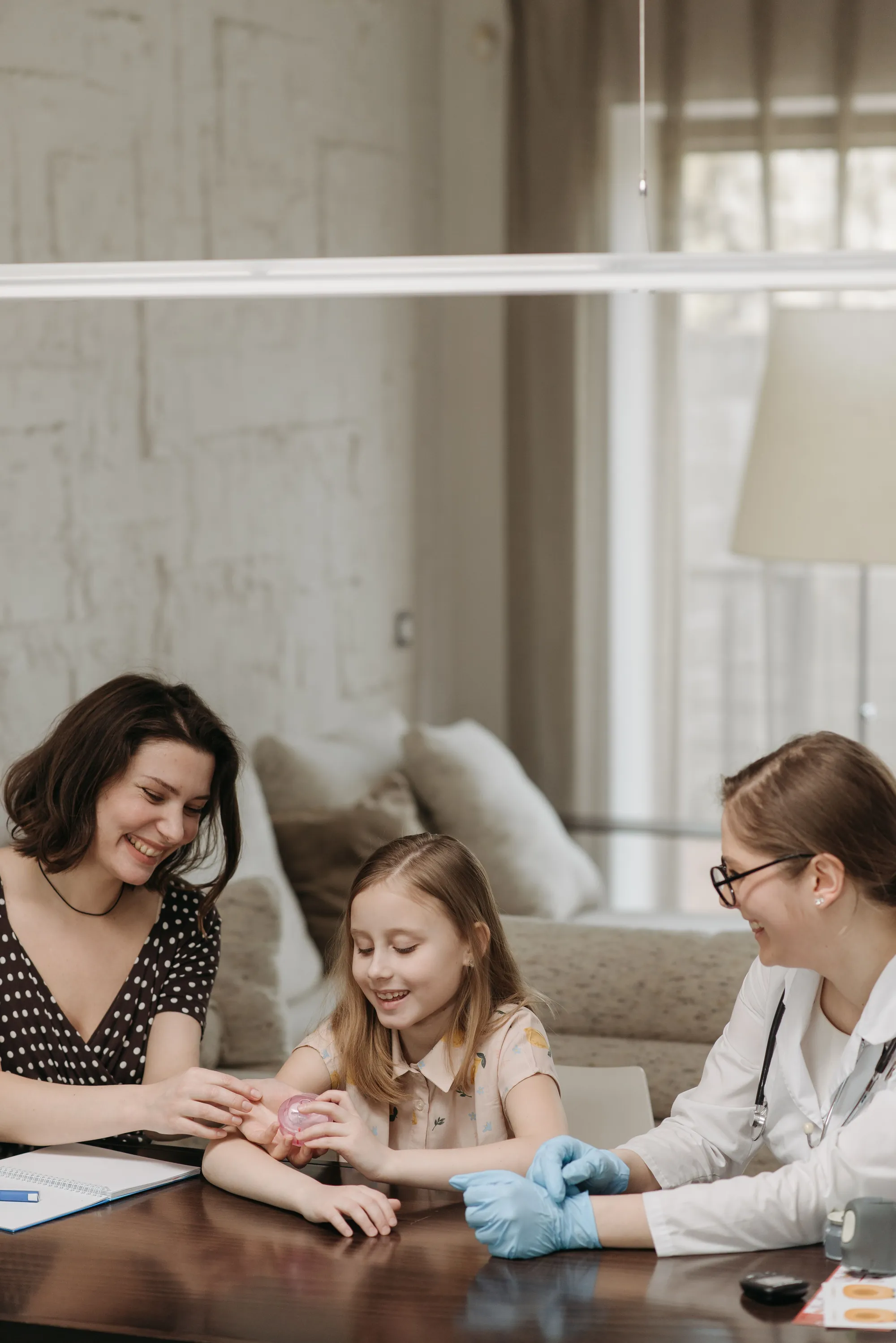 A doctor speaking with a child and her parent during a consultation
